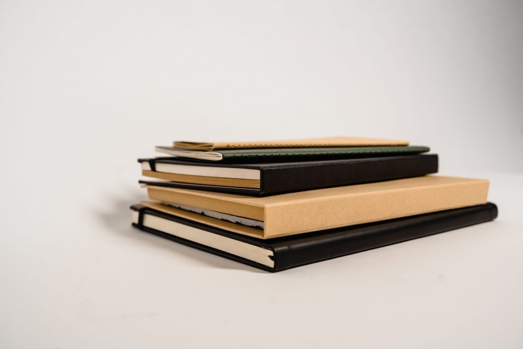 A stack of assorted notebooks with different colors and textures on a white background.